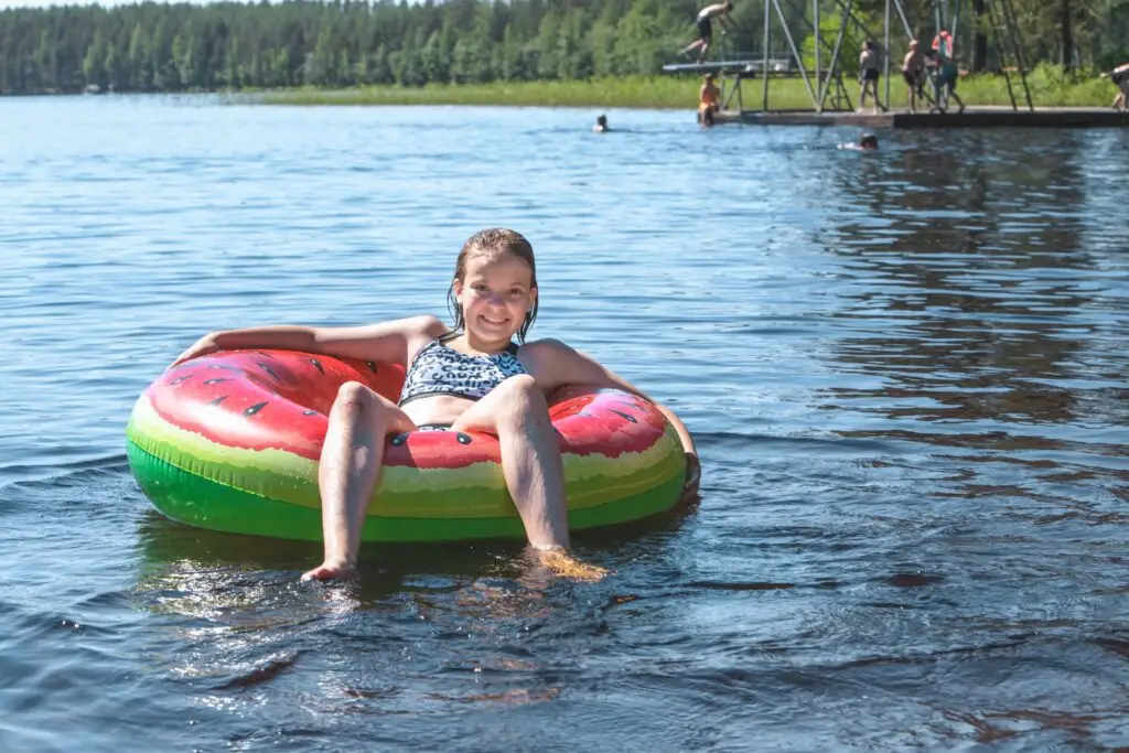 lapsi uimarenkaalla uimarannalla ja hyppytorni taustalla