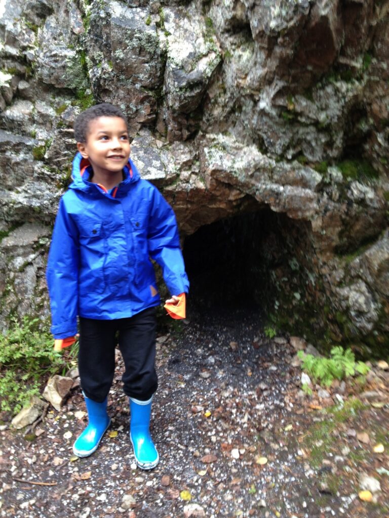 sinitakkinen ja sinisissä kumppareissa poika luolan edessä